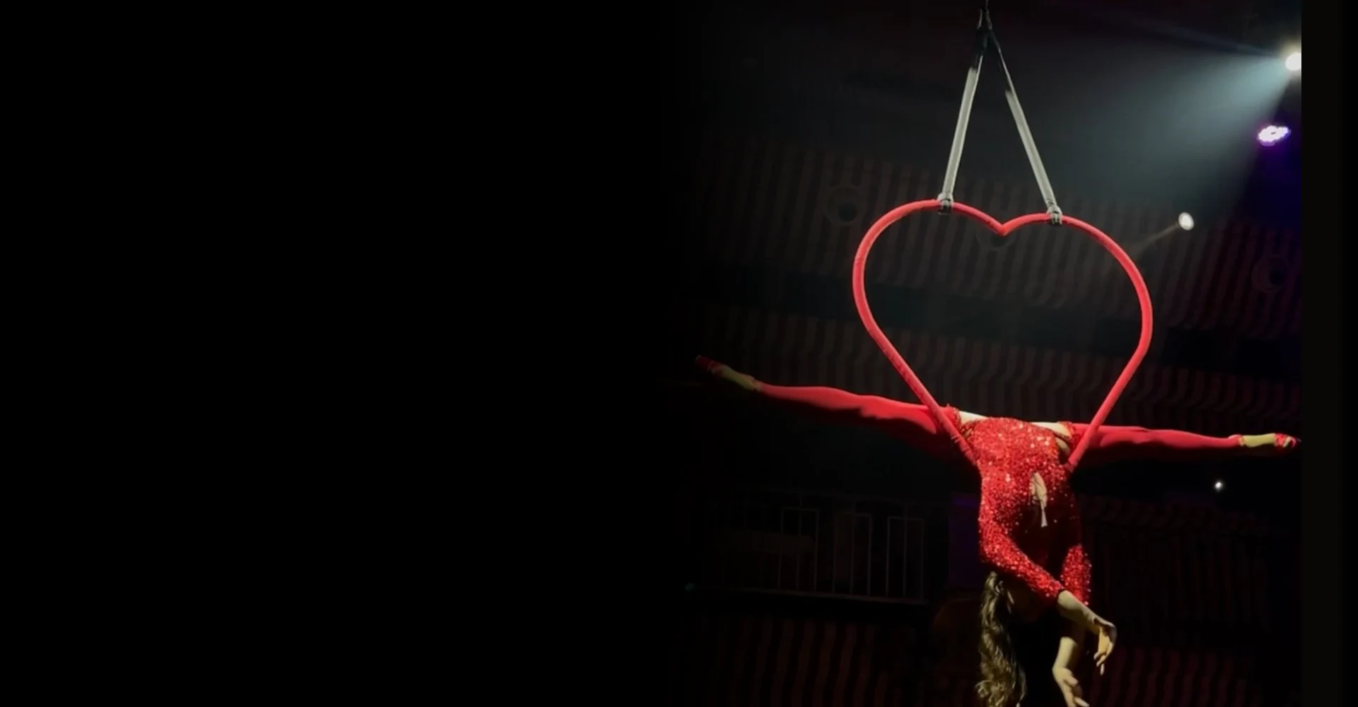 Zofia aerial acrobat performing dramatic split in red sparkle costume on heart-shaped lyra